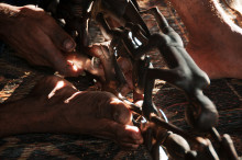 Asmat craftsman carving traditional wood figures near Agats, West Papua